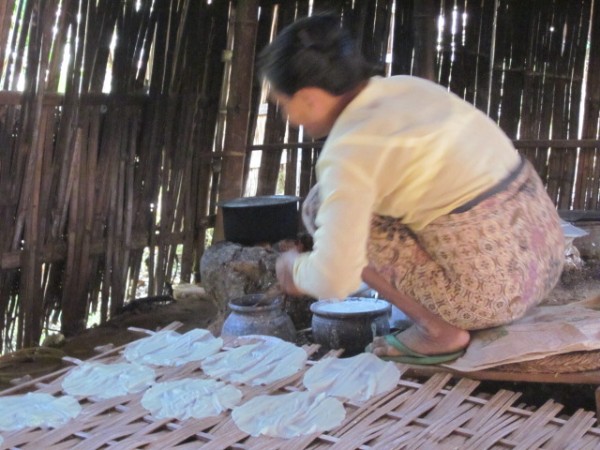 Woman making rice crackers over a charcoal fire. She makes up to 400 per day and sells them in the market.